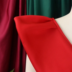 Detalle del diseño de hombros plisados en un vestido de noche rojo con brillo