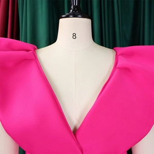 Detalle de vestido rosa intenso con escote en V profundo y volantes plisados en hombros