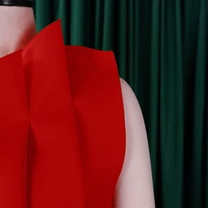 Close-up detail of high-waisted pleated red evening gown with structured fabric texture