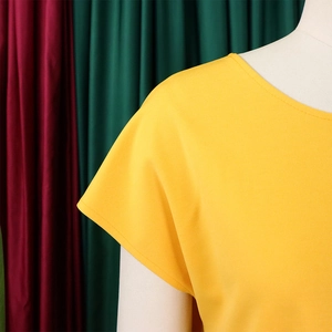 Detail of yellow round neck short sleeve top showing fabric texture and neckline stitching
