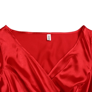 Detailed close-up of the elegant crossover V-neckline and silky red satin fabric texture