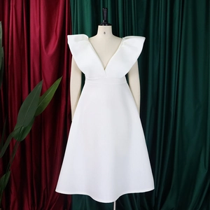 Detalle de vestido blanco de fiesta con escote en V, volantes estructurados y corte en A
