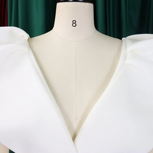 Detalle de un vestido de noche blanco con escote en V profundo y mangas abullonadas