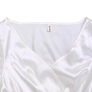 Detail of the V-neckline and S size label on a white satin pleated dress for women