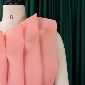 Detail of pink off-shoulder evening dress with ruffled neckline and pleated layers