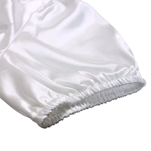 Detailed view of elastic pleated cuffs on a white satin V-neck dress with silky texture