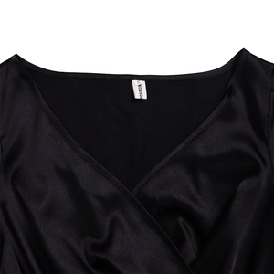 Close-up of the V-neckline and HOSIS GIRLS brand label on a black satin dress