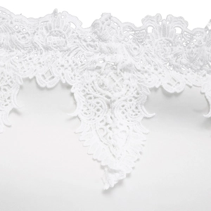 Close-up of intricate white lace embroidery and delicate cutout patterns on a dress