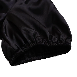 Detailed macro view of elasticated cuffs on a black satin dress with pleated texture