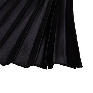 Detailed view of the fine vertical pleats and smooth black fabric on the summer dress
