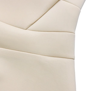 Primer plano del vestido beige con cuello en V profundo y detalles de costura en tejido
