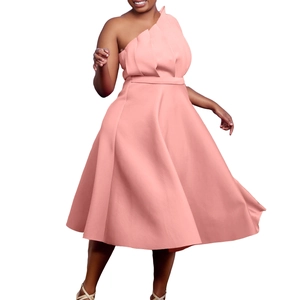 Détail d'une robe rose pêche à une épaule montrant des plis étagés et une coupe trapèze haute