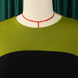 Dettaglio della cucitura dello scollo su un abito in maglia bicolore verde e nero da donna