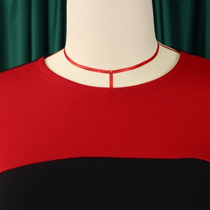 Dettaglio dello scollo color-block rosso e nero su un elegante abito in tessuto elastico