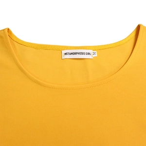 Close-up of ginger yellow knit top with round neckline and Metamorphosis Girl brand label