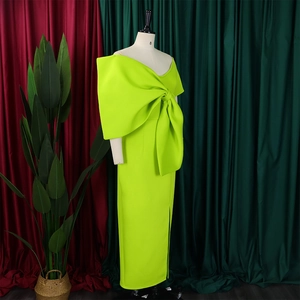 Detail eines neongrünen One-Shoulder-Kleides mit großer Schleife und elegantem Seitenschlitz