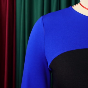 Dettaglio dell'abito in maglia bicolore blu e nero con pannelli curvi e scollo rotondo