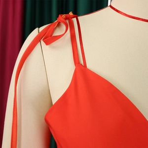 Dettaglio dell'abito rosso con scollo a V e spalline sottili con eleganti fiocchi decorativi