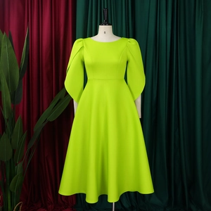 Detail of elegant neon green midi dress featuring structured cape sleeves and flared hemline