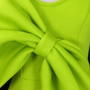 Detail einer großen Schleifendekoration an einem neongrünen Abendkleid mit Schlitz
