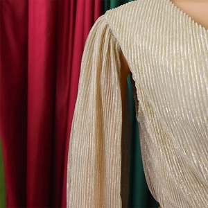 Detail view of champagne gold pleated gown with puff sleeves and metallic luster fabric