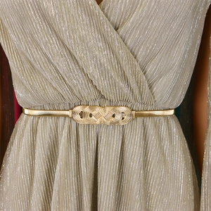 Detail of elegant gold elastic metal belt with interlocking textured buckle on dress