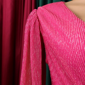 Close-up of rose red pleated cape dress featuring shiny metallic thread texture