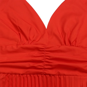 Dettaglio dell'abito rosso con scollo a V, vita alta ed elegante trama in tessuto plissettato
