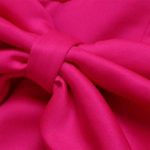 Detail eines großen rosa Knotens auf einem Abendkleid mit seidiger Stoffstruktur