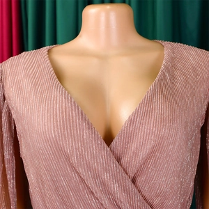 Close-up of pink V-neck dress featuring glittery pleated fabric and wrap design detail