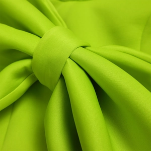 Detail einer großen neongrünen Knotenschleife an einem sexy Partykleid mit Schlitz