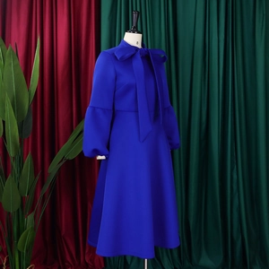 Detail of blue high-waist dress featuring large bow-tie neckline and puff lantern sleeves