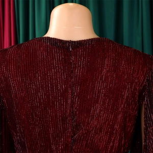 Detail of burgundy pleated dress featuring shimmering metallic threads and a back hidden zipper