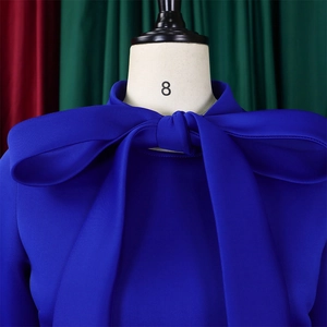 Close-up of royal blue puff sleeve dress featuring a large decorative neck bow detail