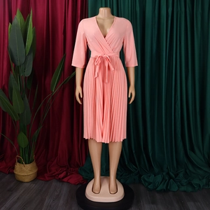 Close-up of peach pink V-neck pleated dress featuring a wrap waist tie and 3/4 sleeves