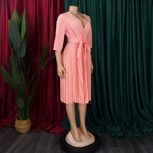 Detail of pink pleated wrap dress featuring a V-neckline and waist tie on a mannequin