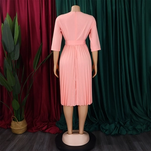 Detail view of the pleated skirt hem and waist belt on a light pink midi dress