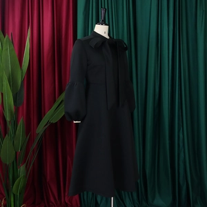 Detail of elegant black dress with oversized bow neckline and puff lantern sleeves