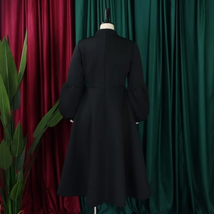 Detail of plus size black party dress featuring lantern sleeves and a flared skirt design