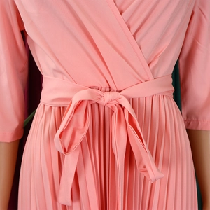 Detail of pink pleated chiffon dress featuring V-neckline and tie waist belt detail