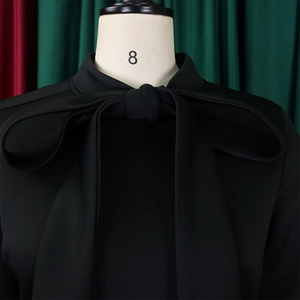 Detail of elegant black dress featuring a large bow and premium textured fabric