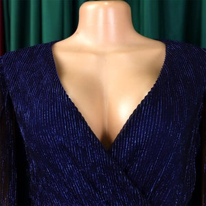 Detailed macro view of deep blue pleated fabric with shimmering metallic sheen and V-neckline