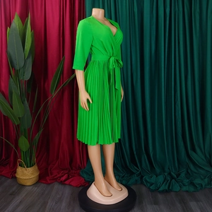 Detail of elegant bright green V-neck pleated wrap dress with matching waist tie belt