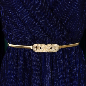 Close-up of golden elastic metal belt with intricate infinity weave buckle on navy dress