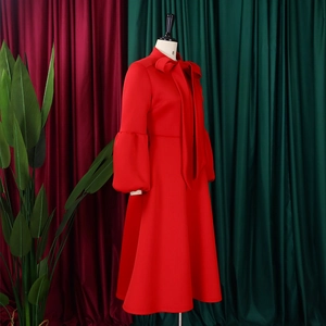 Detail view of red puff sleeve dress showing oversized bow tie and lantern cuffs