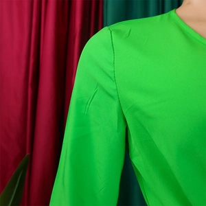 Detail view of the shoulder seam and pleated fabric texture on a lime green V-neck dress