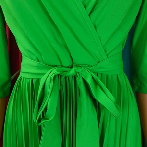 Close-up of bright green pleated dress with tie-waist bow and fine textured fabric
