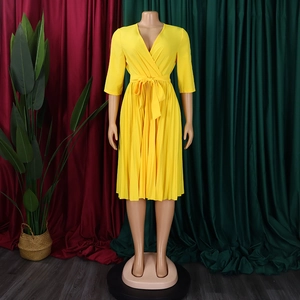 Detailed view of yellow V-neck pleated dress featuring waist tie and accordion pleats