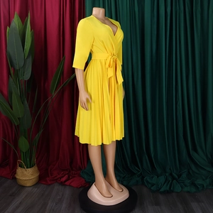 Detail of yellow pleated midi dress featuring a V-neck wrap design and waist tie belt