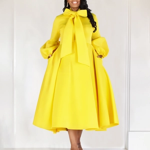 Detail of a bright yellow dress with a large bow collar and puff long sleeves